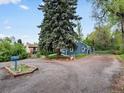 Cozy house with mature trees and a spacious gravel driveway with unique garden planter at 1580 Youngfield St, Lakewood, CO 80215