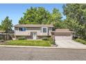Inviting two-story home featuring a lush green lawn, mature trees, and an attached garage at 7331 S Webster St, Littleton, CO 80128