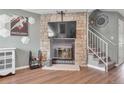 Close up of a stone fireplace with mounted TV and white railing staircase at 9240 W Ontario Dr, Littleton, CO 80128