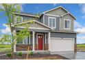 Two-story home featuring gray siding, stone accents, a red front door, and a two-car garage at 4757 Windmill Dr, Brighton, CO 80601