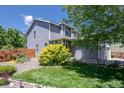 Exterior showcases a gray home with a well-maintained yard, lush green grass, and a lovely garden bed at 7871 Ogden Ct, Denver, CO 80229