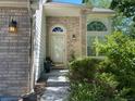 Inviting front entrance with brick accents, a storm door, and lush landscaping at 7158 Torrey St, Arvada, CO 80007