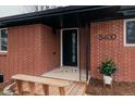 Welcoming front porch with a modern front door, red brick facade, and cozy bench at 3400 Moore St, Wheat Ridge, CO 80033