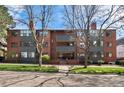 Three-story brick apartment building with gray accents and manicured lawn under a sunny blue sky at 534 E 7Th Ave # 206, Denver, CO 80203
