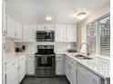 Bright kitchen featuring white cabinets, stainless steel appliances, quartz countertops, and a garden window at 3657 S Laredo St # E, Aurora, CO 80013