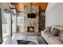 Bright living room with a striking stone fireplace, vaulted wooden ceiling and sliding glass door at 13635 E Yale Ave # D, Aurora, CO 80014
