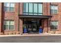 Close up of a brick building entrance with glass doors and blue potted plants at 155 S Monaco Street Pkwy # 311, Denver, CO 80224