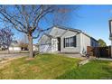 Well-maintained home with lush lawn, mature tree, and a two-car attached garage, set against a clear blue sky at 5611 S Sicily Cir, Aurora, CO 80015