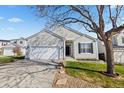 Inviting single-Gathering home featuring a well-maintained lawn, mature trees, and an attached two-car garage at 5611 S Sicily Cir, Aurora, CO 80015