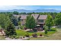 Expansive backyard with a deck, play area, manicured lawn, mature trees and mountain views at 14652 Kalamath Ct, Westminster, CO 80023