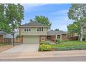 Charming two-story home with green siding, brick accents, a two-car garage, and manicured landscaping at 8116 W Fremont Dr, Littleton, CO 80128