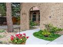 A stone walkway leads to the main entrance, framed by an arched brick walkway and vibrant floral landscaping at 8793 E Monmouth Pl, Denver, CO 80237