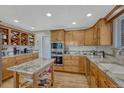 Eat-in kitchen featuring custom wood cabinets, an island, and modern appliances at 5 Catamount Ln, Littleton, CO 80127
