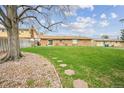 Expansive backyard featuring a lush green lawn, mature trees, and a stone path, perfect for outdoor enjoyment at 490 Potomac Way, Aurora, CO 80012