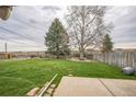 Large, green backyard with mature trees and a fence providing privacy and space for outdoor activities and relaxation at 490 Potomac Way, Aurora, CO 80012