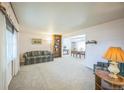 Cozy living room with plush carpeting, neutral walls, and a large window for natural light creating a welcoming space at 490 Potomac Way, Aurora, CO 80012
