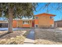 Charming orange brick home with mature tree, featuring a red front door and walkway at 3164 Scranton St, Aurora, CO 80011