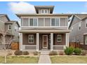 Inviting two-story home with a covered brick porch and manicured landscaping at 631 E Hinsdale Ave, Littleton, CO 80122