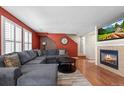 Comfortable living room with a cozy fireplace, hardwood floors, and bright windows with shutter blinds at 13884 Lilac St, Thornton, CO 80602