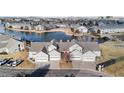 Aerial view of lakeside townhomes with garages, landscaping, and nearby walking bridge at 15555 E 40Th Ave # 6, Denver, CO 80239