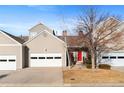 Townhome exterior featuring a two-car garage, red front door, and tidy landscaping at 15555 E 40Th Ave # 6, Denver, CO 80239