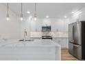 Modern white kitchen with stainless steel appliances and pendant lighting at 1308 Snowberry Ln # 303, Louisville, CO 80027