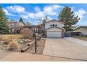 Home with a front yard featuring mature landscaping and a long driveway leading to an attached garage at 8690 E Chenango Ave, Denver, CO 80237