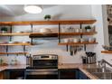 Well-organized kitchen featuring open wooden shelving, granite countertops, and modern appliances at 19044 E 16Th Ave, Aurora, CO 80011