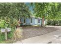 Quaint blue house featuring mature trees, small garden, and gravel landscaping for a natural aesthetic at 3224 S Dudley St, Lakewood, CO 80227