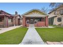 Craftsman style home featuring a brick facade, covered porch, and a lush green lawn at 586 S Corona St, Denver, CO 80209