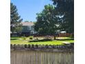 View of the backyard with mature trees, green space, and a community playground beyond the fence at 970 S Peoria St, Aurora, CO 80012