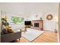 Comfortable living room featuring a cozy brick fireplace and a large window with natural light at 12193 W New Mexico Pl, Lakewood, CO 80228