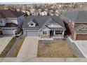 Aerial view of a two-story home with gray siding, stone accents, attached garage, and covered front porch at 20795 Scenic Park Dr, Parker, CO 80138
