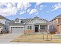 Inviting two-story home featuring gray siding, stone accents, an attached garage, and a charming covered front porch at 20795 Scenic Park Dr, Parker, CO 80138