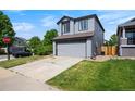 This home features a well-manicured lawn, gray siding, and an attached two-car garage at 8791 Starwood Ln, Parker, CO 80134