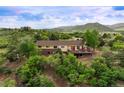 A sprawling home with a large wooden deck surrounded by a vibrant green landscape with rolling hills at 3850 Hopi Dr, Sedalia, CO 80135