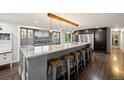An open kitchen with a large island, marble countertops, pendant lighting, stainless steel appliances, and dark hardwood floors at 3850 Hopi Dr, Sedalia, CO 80135