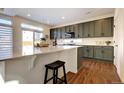 Modern kitchen with an island, counter seating, gray cabinets and stylish countertops at 16357 E 111Th Pl, Commerce City, CO 80022
