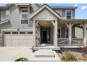 Inviting front entrance with covered porch featuring detailed woodwork, stone accents, and a multi-car garage at 141 Back Nine Dr, Castle Pines, CO 80108