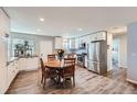 Bright kitchen features white cabinetry, stainless steel appliances, and a cozy dining area with wood table at 14798 E Temple Dr, Aurora, CO 80015