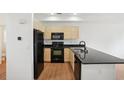 Modern kitchen featuring black appliances, light wood cabinets, and dark countertops at 2253 Coronado Pkyn # D, Denver, CO 80229