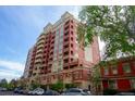 Exterior of a high-rise condo building with red brick and tan accents, and cars parked on the street at 1950 N Logan St # 102, Denver, CO 80203