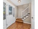 Bright entryway featuring hardwood floors, a staircase with white banister, and a glass-paneled front door at 6827 Vivian St, Arvada, CO 80004