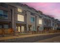 Dusk view of modern townhomes featuring brick and siding exteriors, wooden fences, and rooftop decks under a vibrant, pink-tinged sky at 3520 W Conejos Pl # 11, Denver, CO 80204