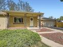 Inviting front porch with decorative wrought iron supports and manicured landscaping at 50 Yarrow St, Lakewood, CO 80226
