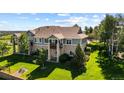 Spacious multi-story home with stone accents, a balcony, a well-maintained lawn and mature trees at 7713 S Zante Ct, Aurora, CO 80016