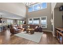 Spacious living room featuring a soaring ceiling, large windows, hardwood floors, and comfortable leather seating at 696 Eveningsong Dr, Castle Rock, CO 80104
