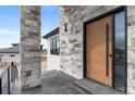 Close up on front entrance with stone pillars and a modern wooden front door with glass at 10291 E 142Nd Ave, Brighton, CO 80602