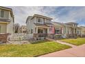 Inviting two-story home with landscaped front yard, sidewalk and a charming American flag on the porch at 14332 Craftsman Way, Broomfield, CO 80023
