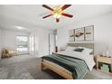 Well-lit bedroom featuring a bed, modern lighting, neutral walls and carpet, and natural light from the window at 12065 E Kentucky Ave, Aurora, CO 80012
